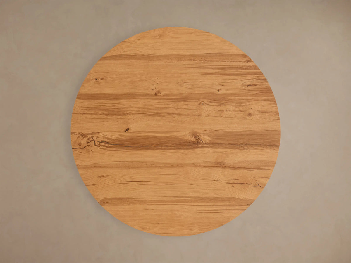 Top view of a round Kensington Round Reclaimed Dining Table with a natural light brown reclaimed French oak veneer top, showing wood grain and knots.