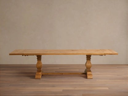 Kensington Reclaimed Dining Table with a light wood rectangular top, supported by two ornate turned pedestal bases, on a wood floor.
