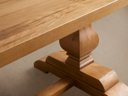 Kensington Reclaimed Dining Table, light natural wood, rectangular top, two ornate pedestal bases with stretcher, on wood floor.