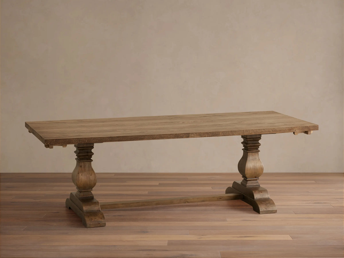 Kensington Reclaimed Dining Table in natural wood finish with two sturdy carved pedestal legs and a rectangular top, placed on a wooden floor.