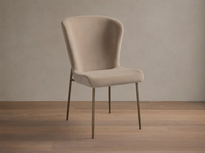Kirsten High Back Dining Chair, upholstered in light beige, featuring a curved high back and slim metallic bronze legs, angled.