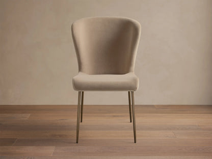 Kirsten High Back Dining Chair, upholstered in light beige, featuring a curved high back and slim metallic bronze legs, angled.