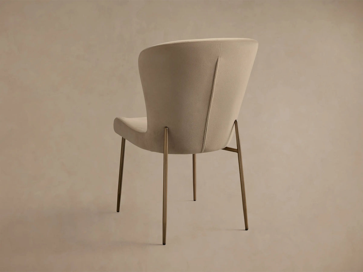 Close-up of Kirsten High Back Dining Chair. Light beige, textured fabric seat and curved back with dark powder-coated iron frame.