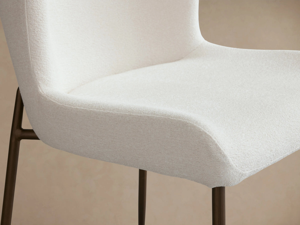 Kirsten Dining Chair with a white, curved backrest and seat. Brown iron legs are visible, showing a textured powder-coated finish.