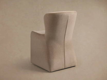 Close-up of the Kirsten Upholstered Dining Chair in soft beige fabric, showing elegant curves of the back and armrest with stitching.