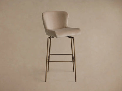 Rear view of the beige Kirsten Swivel Stool with a bronze iron frame and integrated footrest.
