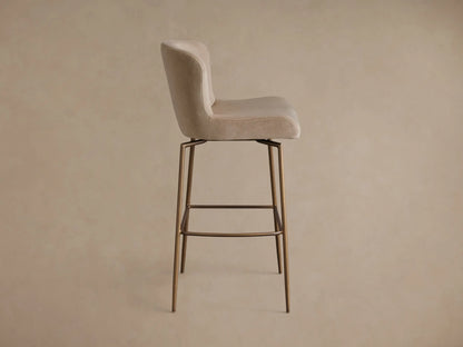 Front view of a beige velvet Kirsten Swivel Stool with a curved back and dark bronze powder-coated metal legs.