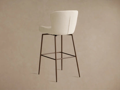 Kirsten Swivel Stool with cream upholstered seat and backrest, black iron legs, and footrest, on a wooden floor.
