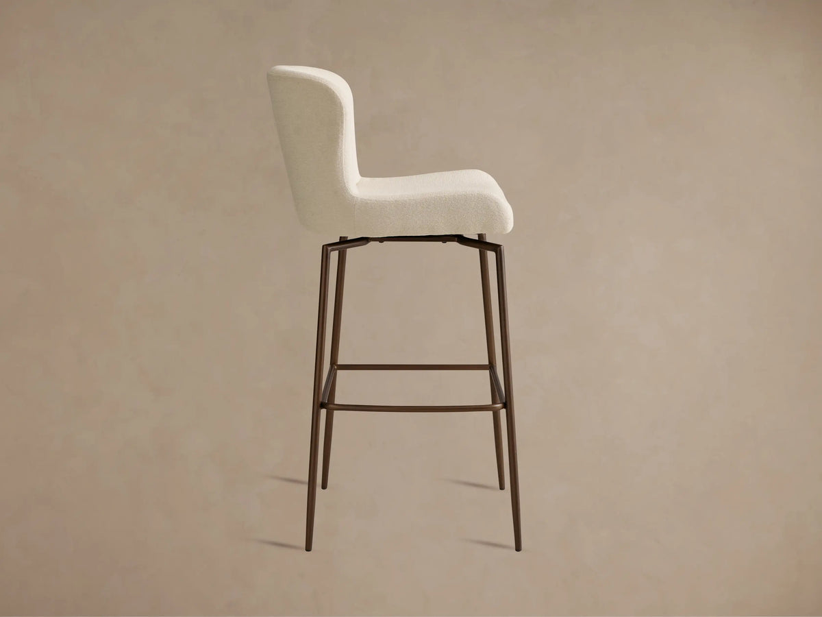 Kirsten Swivel Stool with white upholstered seat, curved backrest, and powder-coated iron legs in a brown finish, viewed from an angle.