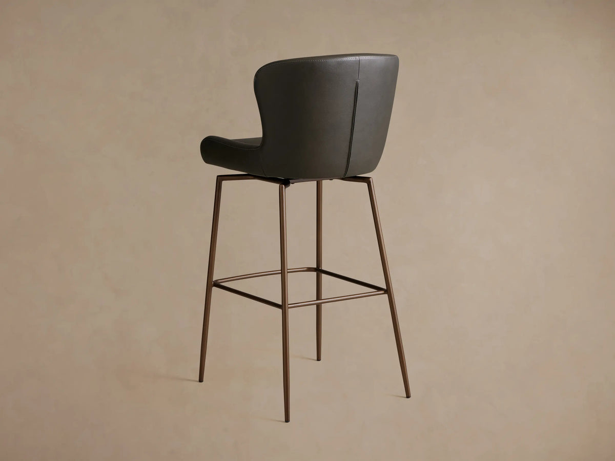 Kirsten Faux Leather Swivel Stool side view showing a dark faux leather seat and back with slender, powder-coated iron legs.