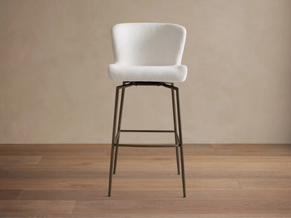 Kirsten Swivel Stool with a plush, white curved seat and black powder-coated iron legs on a wooden floor, side view.