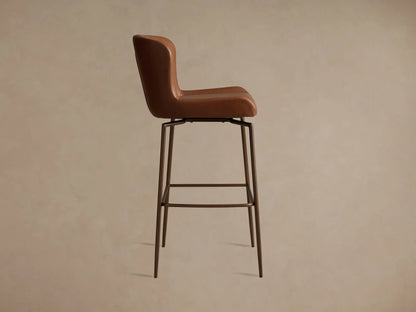 Brown Kirsten Faux Leather Swivel Stool seat close-up, showing smooth faux leather texture with visible stitching, and slender metal legs.