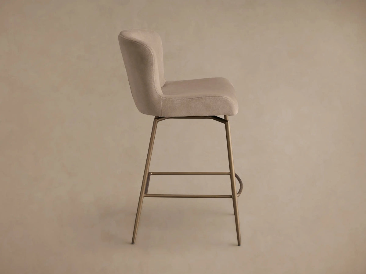 Front view of the cream Kirsten Swivel Stool, featuring a curved back and powder-coated bronze iron frame with a footrest.