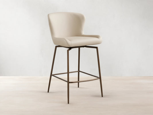 Kirsten Faux Leather Swivel Stool with beige cushioned seat and back, on sleek powder-coated black iron legs, on wooden floor.