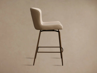 Kirsten Faux Leather Swivel Stool with a beige seat and backrest, bronze powder-coated iron legs, shown from the side profile.