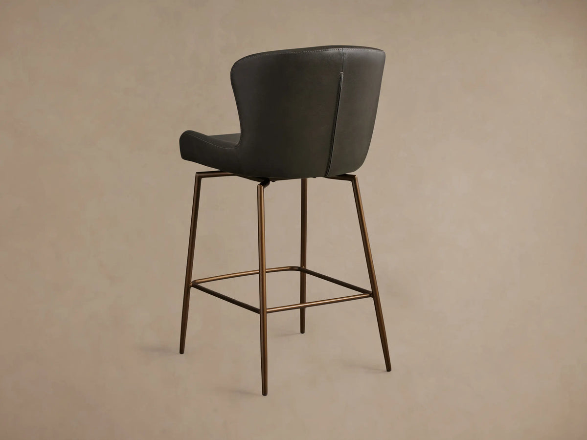 Kirsten Faux Leather Swivel Stool with a dark charcoal seat, curved backrest, and bronze-colored powder-coated iron legs.
