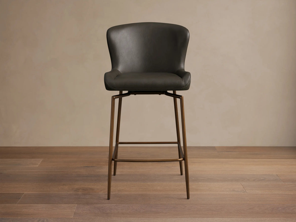 Kirsten Faux Leather Swivel Stool with dark faux leather seat, curved backrest, and slender iron legs, viewed from the side.