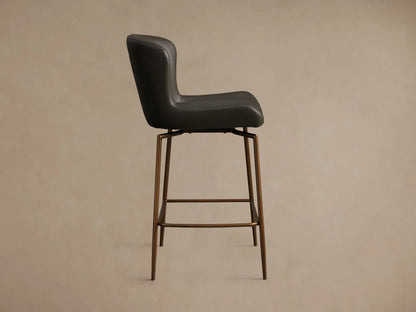 Kirsten Faux Leather Swivel Stool with dark brown seat, curved backrest, and powder-coated iron legs on wooden floor.