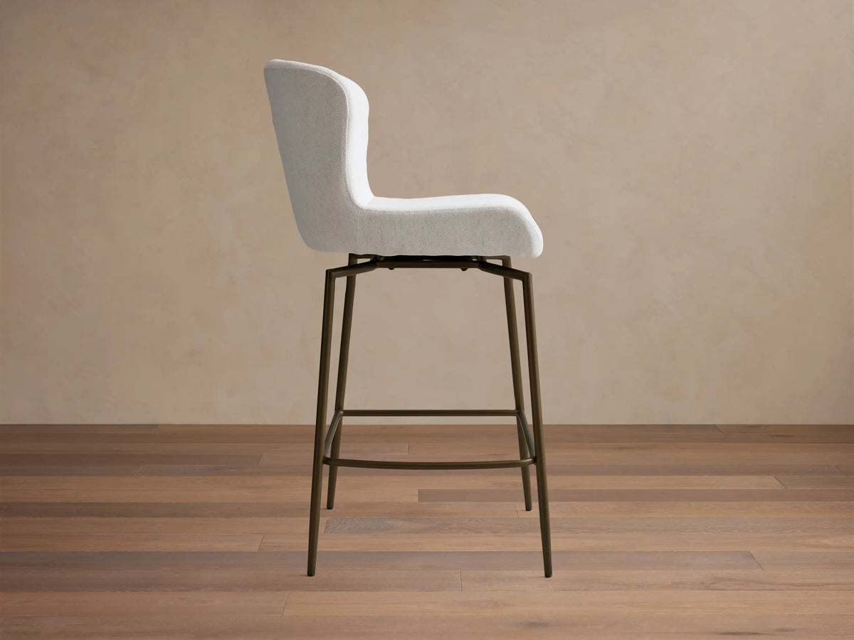 Kirsten Swivel Stool with a white cushioned seat and backrest, mounted on sleek, powder-coated iron legs.