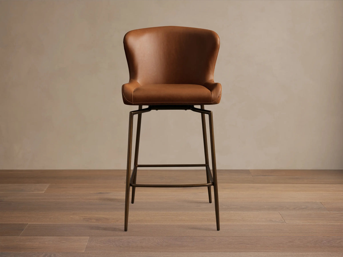 Kirsten Faux Leather Swivel Stool in brown, side view. Iron frame with a powder-coated finish. High back and metal legs.