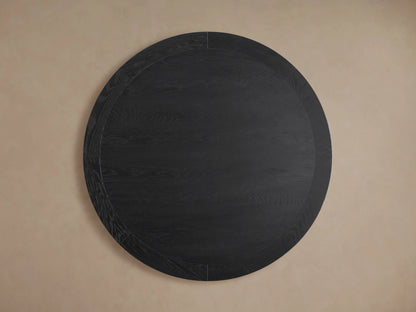 Leighton Round Dining Table with dark oak veneer finish, showcasing wood grain patterns. Supported by a geometric pedestal base.