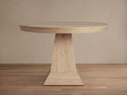 Leighton Round Dining Table with a circular oak veneer top and a unique tapered pedestal base, set on a wooden floor.