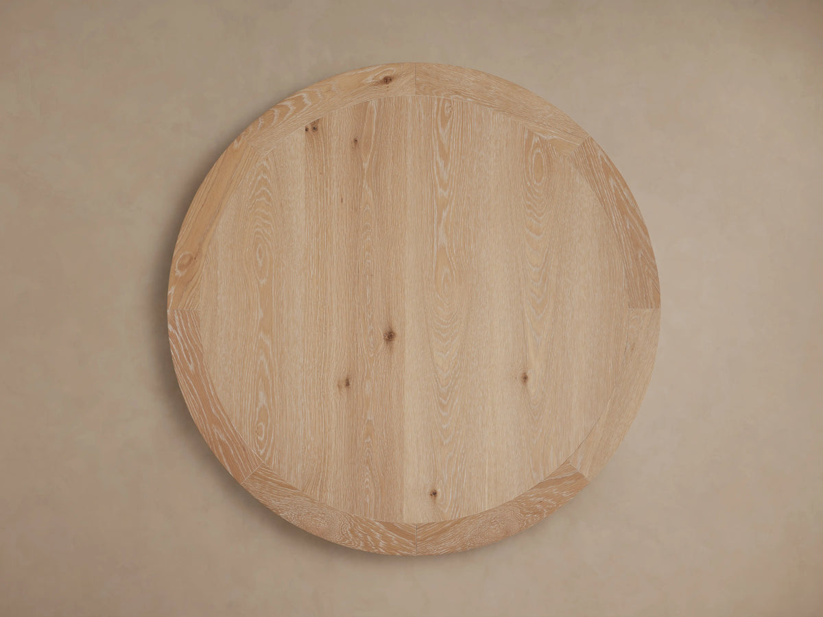 Round wooden tabletop with visible oak grain patterns and smooth edges, supported by a central wooden pedestal base.