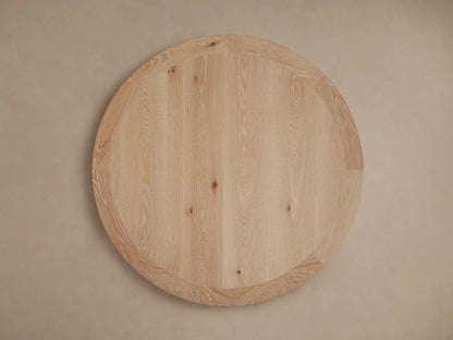 Round wooden tabletop with visible oak grain patterns and smooth edges, supported by a central wooden pedestal base.