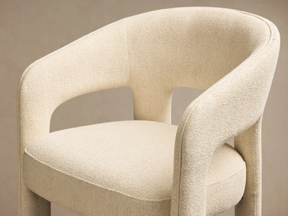 Front view of a cream Lilette Dining Arm Chair, fully upholstered, with a rounded back and thick integrated arms.