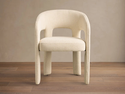 Close-up of the cream textured Lilette Dining Arm Chair, showing its curved back and armrests.