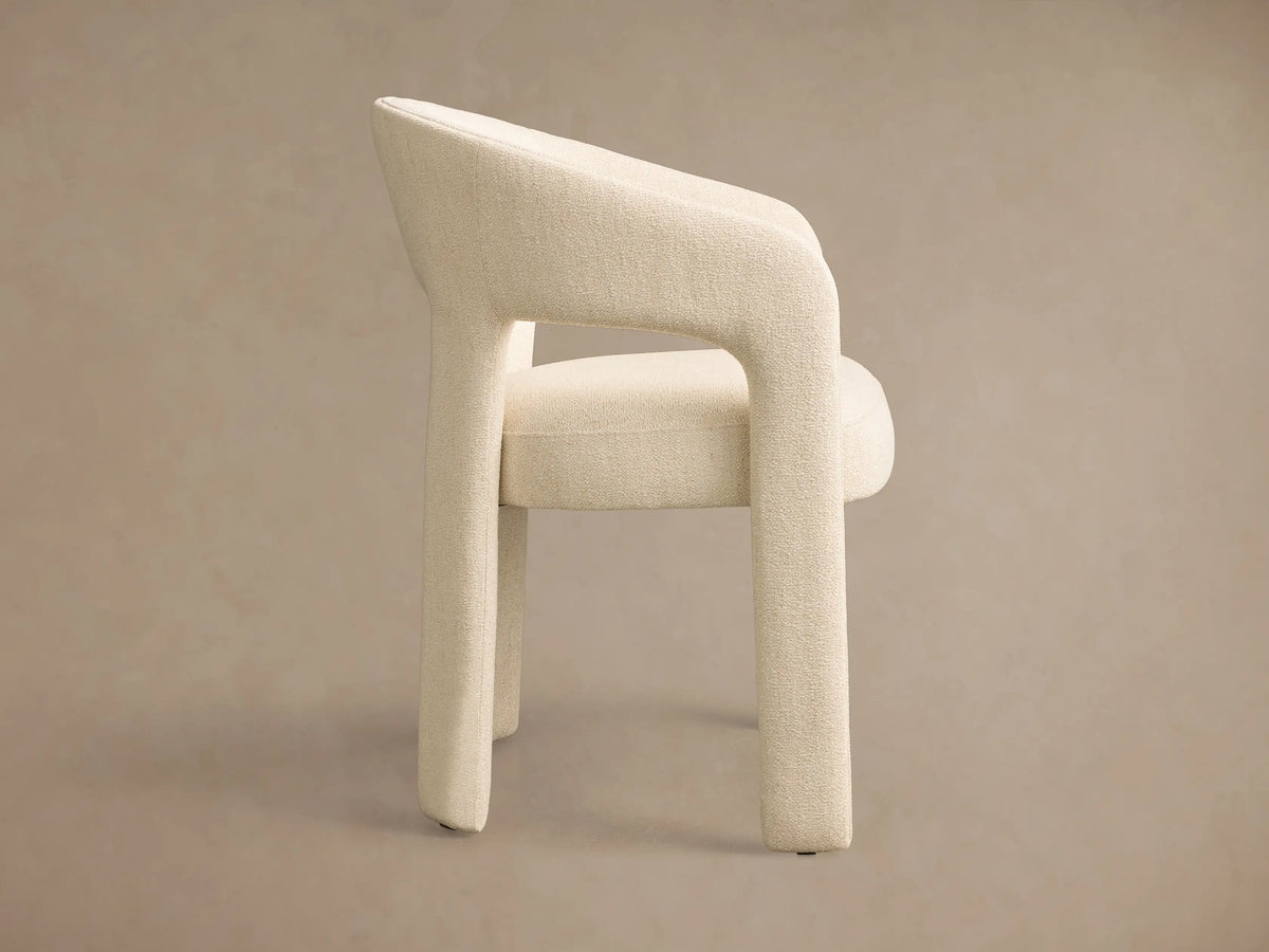 Front view of the cream Lilette Dining Arm Chair, fully upholstered with a curved back and integrated armrests.