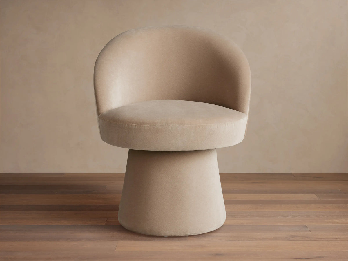 Multiple taupe Lindsay Swivel Dining Chairs, each with a rounded back and cylinder swivel base, around a dining table.