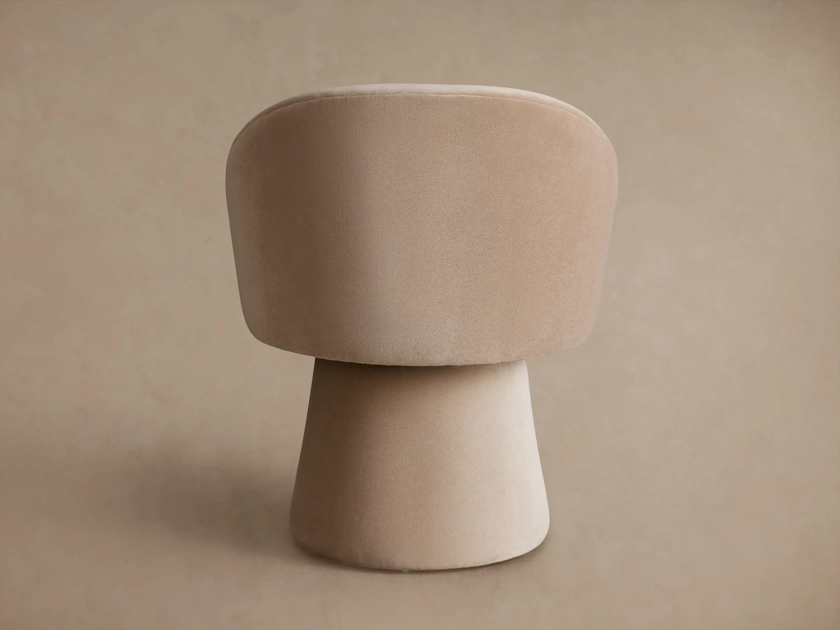 Lindsay Swivel Dining Chair in a neutral beige color, featuring a curved backrest and smooth, rounded pedestal base, side view.