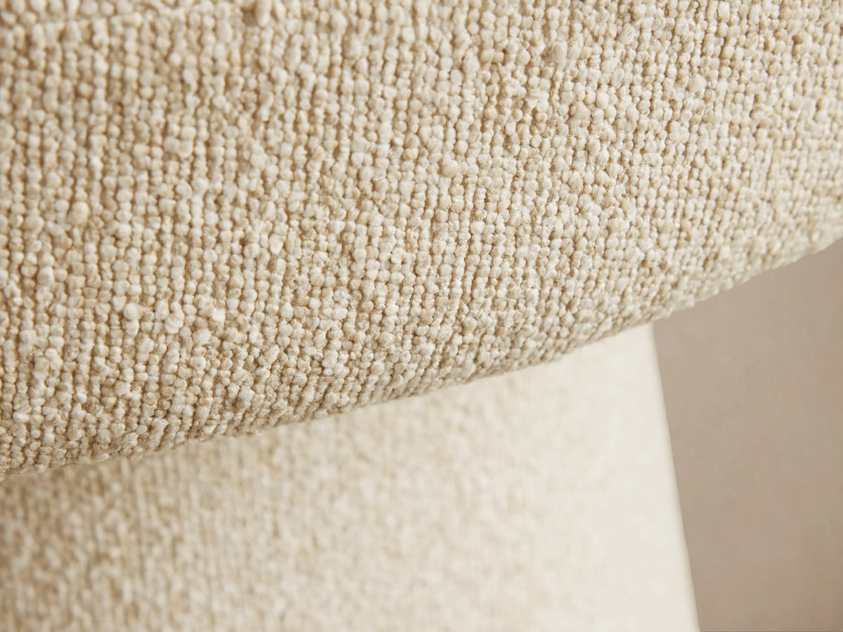 Lindsay Swivel Dining Chair close-up showing textured beige fabric with curved armrest and rounded cushioned seat.