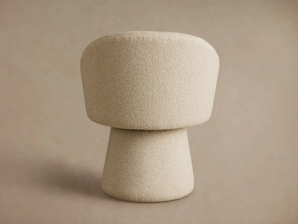 Lindsay Swivel Dining Chair in beige fabric, viewed from the back-left, showcasing its curved backrest and conical base.