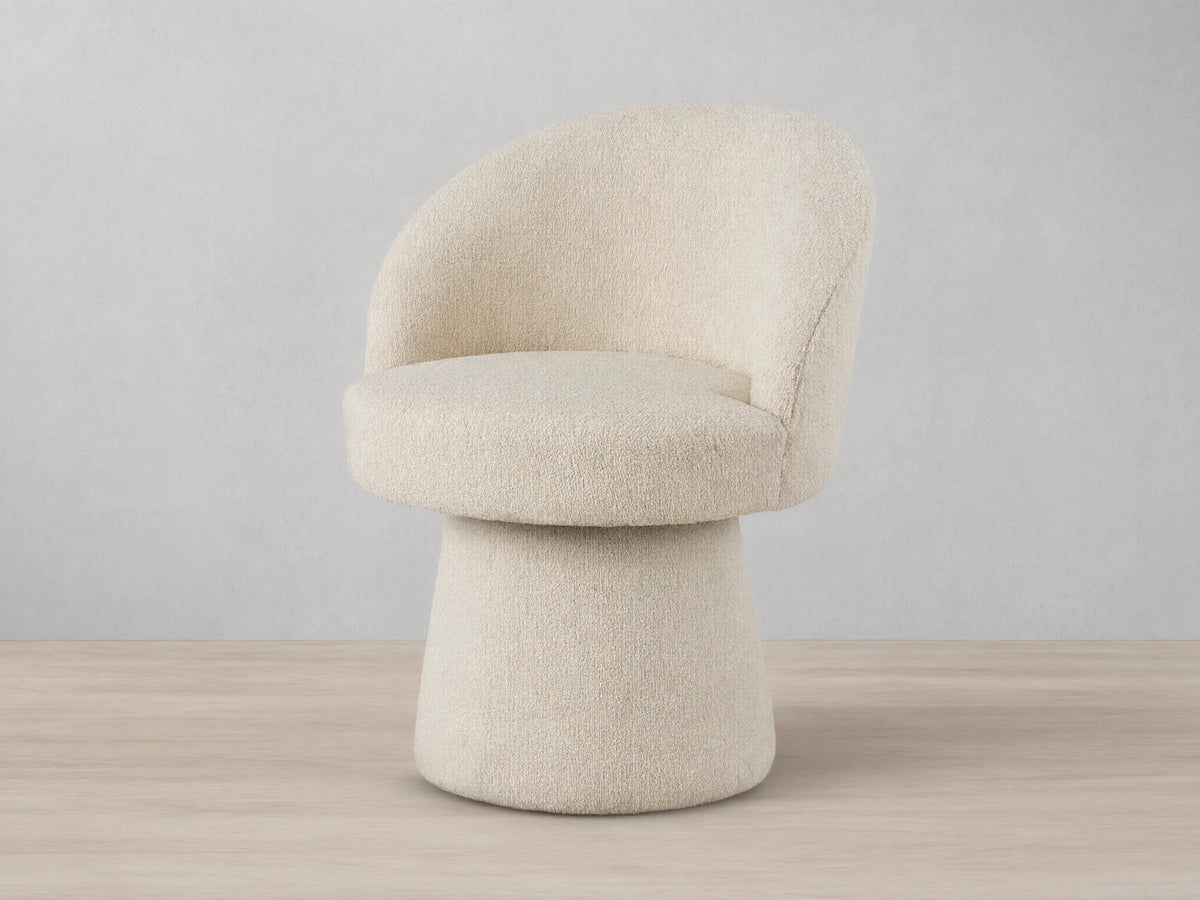 Lindsay Swivel Dining Chair in beige fabric, featuring a curved backrest and round cushioned seat on a tapered base, on a wooden floor.