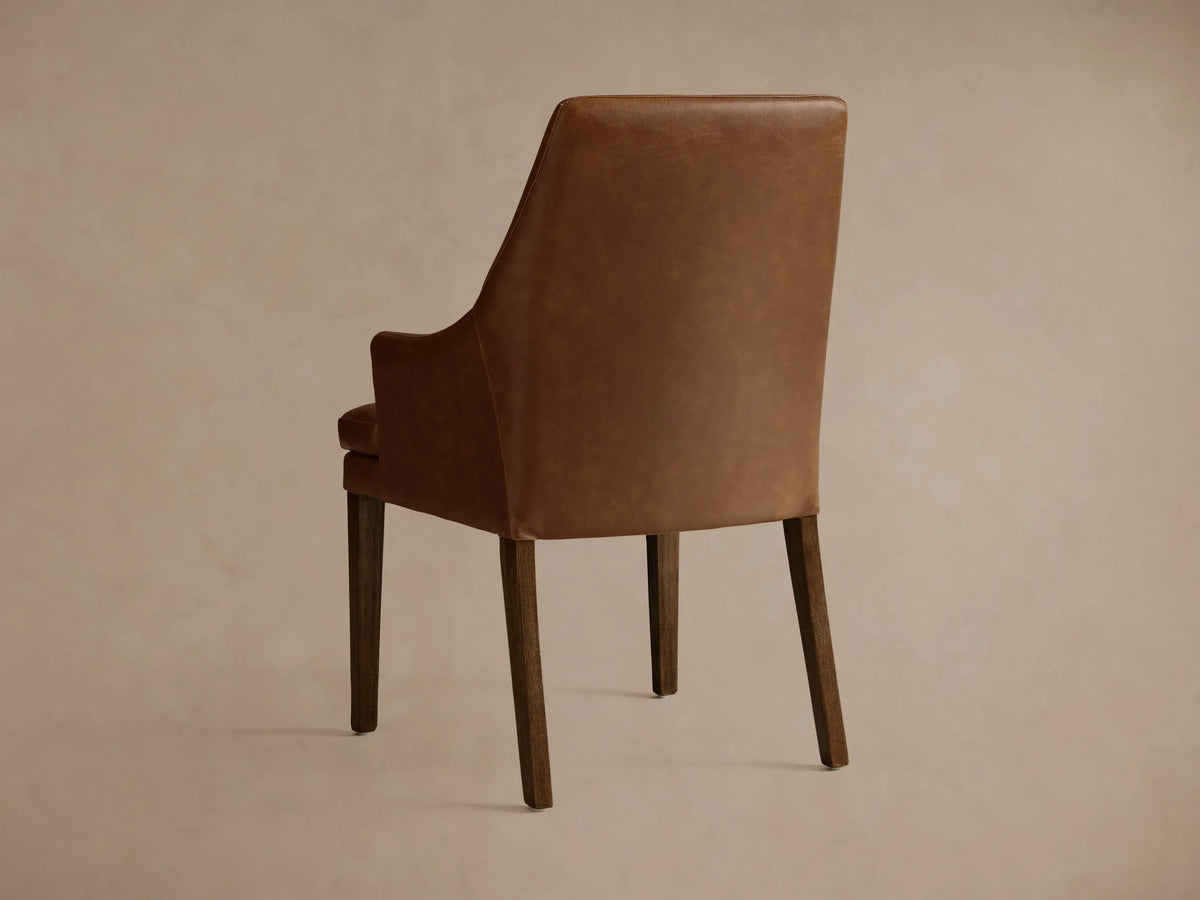Lunden Faux Leather Dining Arm Chair in tan. Close-up of armrest and seat, highlighting smooth texture and stitching detail.