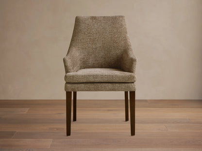 Lunden Dining Arm Chair in textured brown fabric, featuring a gently curved backrest and wooden legs on a wooden floor.
