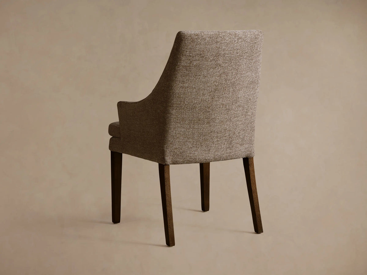 Lunden Dining Arm Chair with textured brown fabric, elegant curved backrest, and armrest, shown in close-up view.