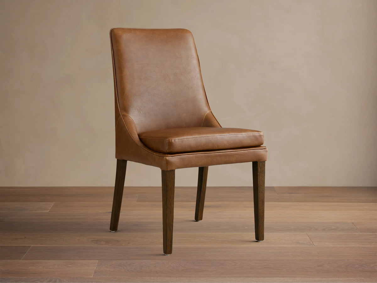 Lunden Dining Side Chair in brown leather with a gently curved backrest and cushioned seat, supported by wooden legs.