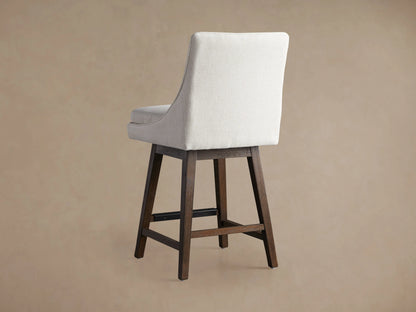 Lunden Swivel Stool, close-up of light beige textured fabric seat and elegantly curved backrest. A dark wooden leg is visible.