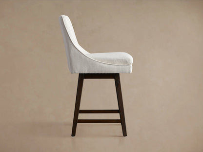 Lunden Swivel Stool, back-right view. Light beige upholstered seat & curved back on dark wood legs with footrests.