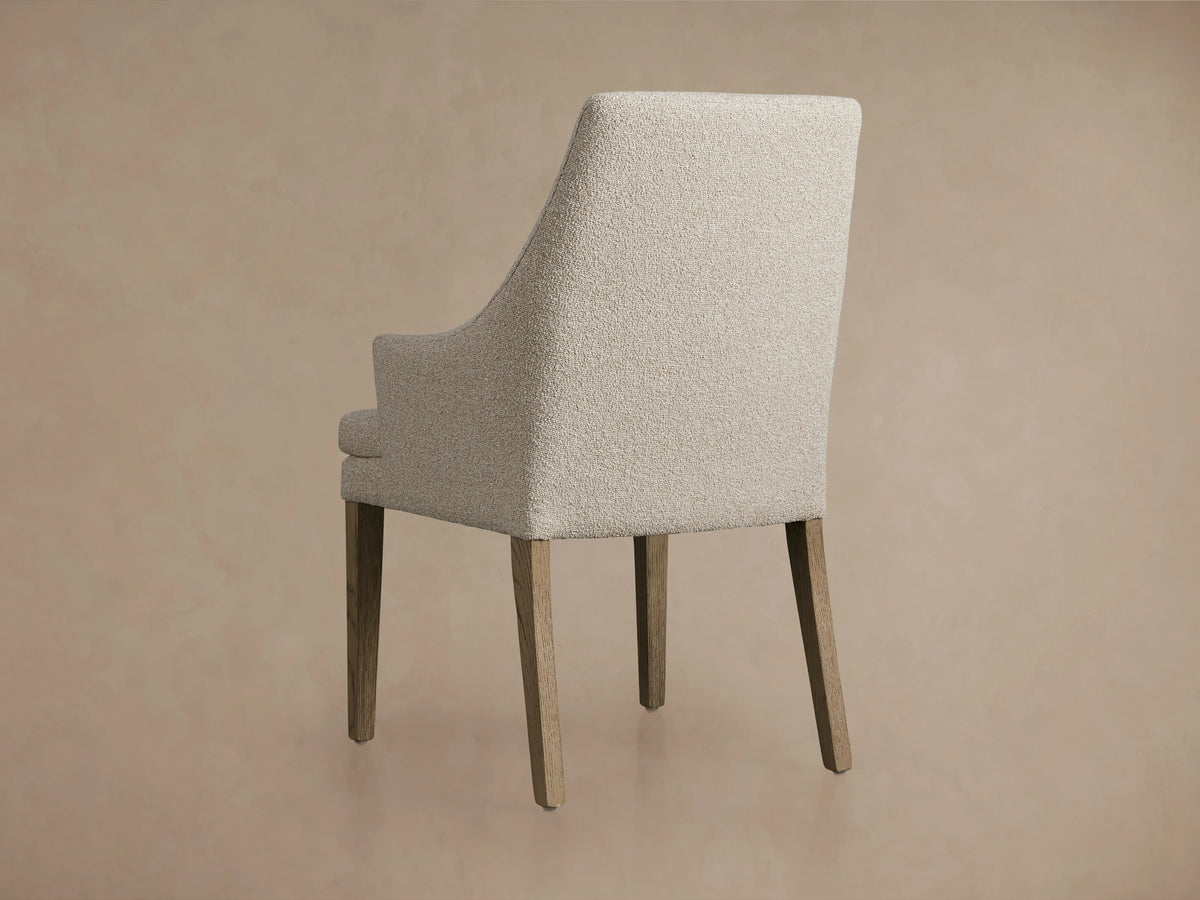 Lunden Dining Arm Chair in Fawn with a gently curved backrest, upholstered in textured light beige fabric, close-up view.