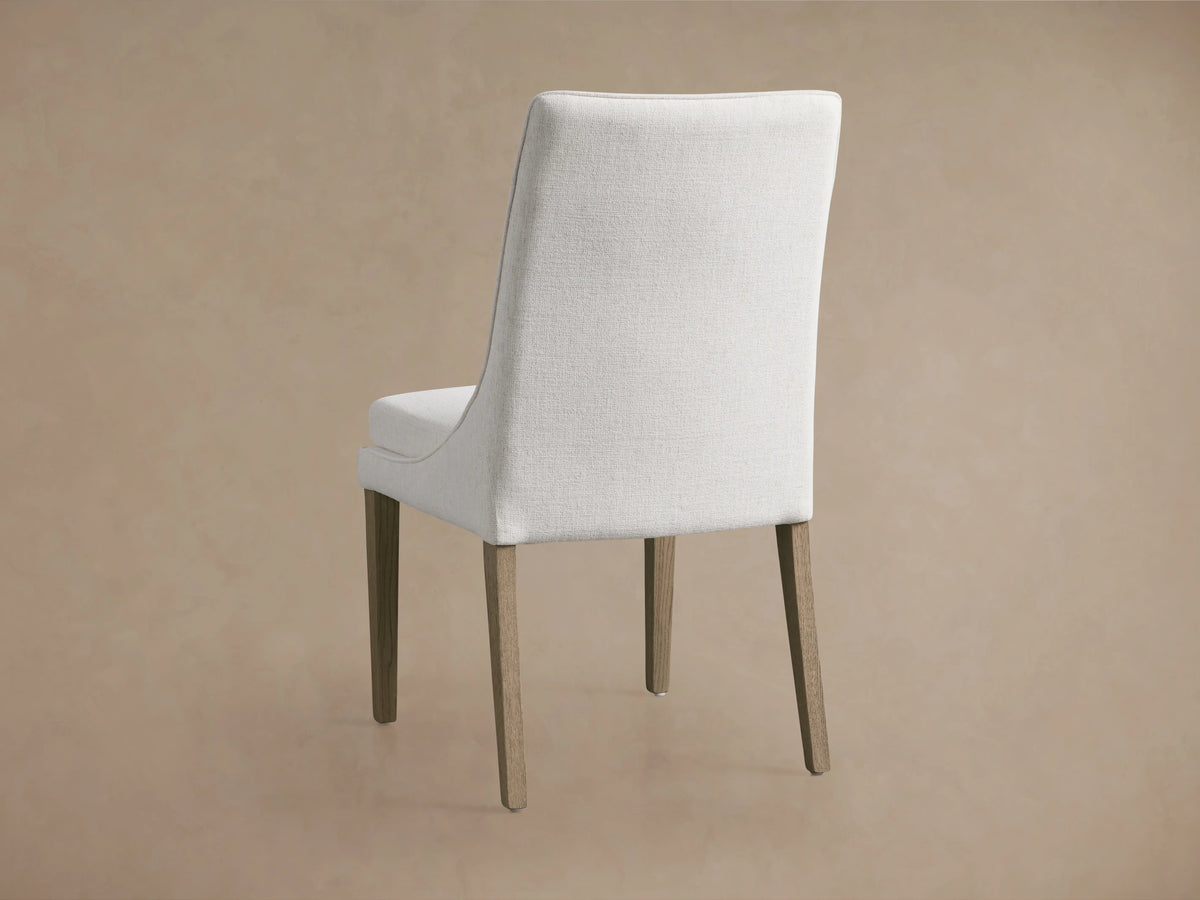 Lunden Dining Side Chair in Fawn featuring a soft ecru cushion, gently curved backrest, and wooden legs on a beige floor.