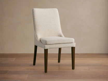 Lunden Dining Side Chair with a beige upholstered seat and backrest, featuring curved design and dark wooden legs on a wooden floor.