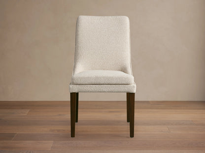 Lunden Dining Side Chair with a beige upholstered seat and backrest, featuring curved design and dark wooden legs on a wooden floor.