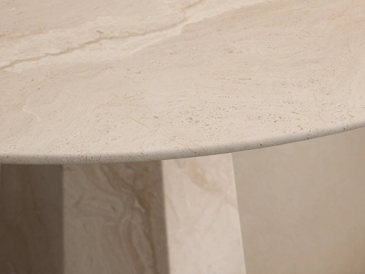 Round light beige marble Modena Dining Table with a geometric pedestal base, centered on a wooden floor.