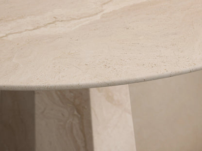 Round light beige marble Modena Dining Table with a geometric pedestal base, centered on a wooden floor.