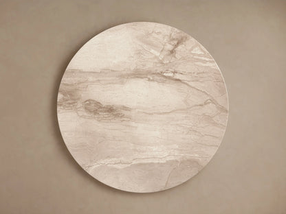 Modena Dining Table with round Italian Beige Coralle marble top & faceted pedestal base, front view, against a beige wall & wooden floor.