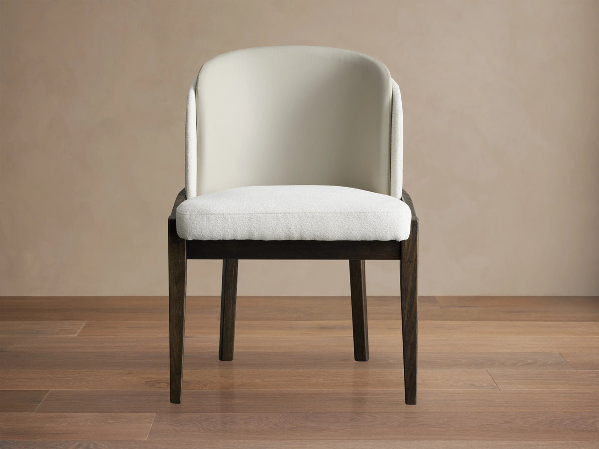 Front view of the Mena Dining Chair with a solid ash wood frame in dark finish. Upholstered in beige faux leather with a softly curved backrest and cushioned seat.